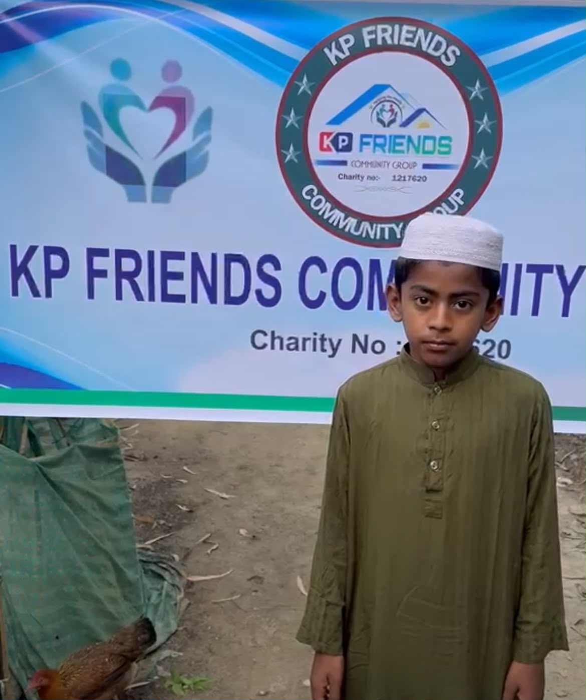 A young boy standing in front of the KP Friends banner